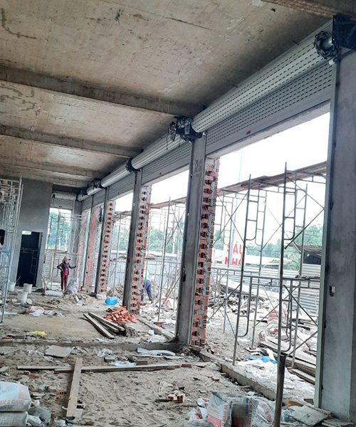 Hộp và trục cửa cuốn đã lắp trên dãy ô cửa lớn của một công trình đang xây
