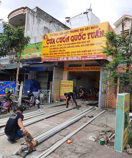 Thợ Quốc Tuấn cắt vật tư cửa cuốn ngay trước cửa hàng của công ty