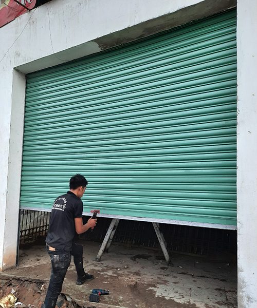 Thợ lắp đặt cửa cuốn tôn Đài Loan màu xanh ngọc cho một nhà đang hoàn thiện