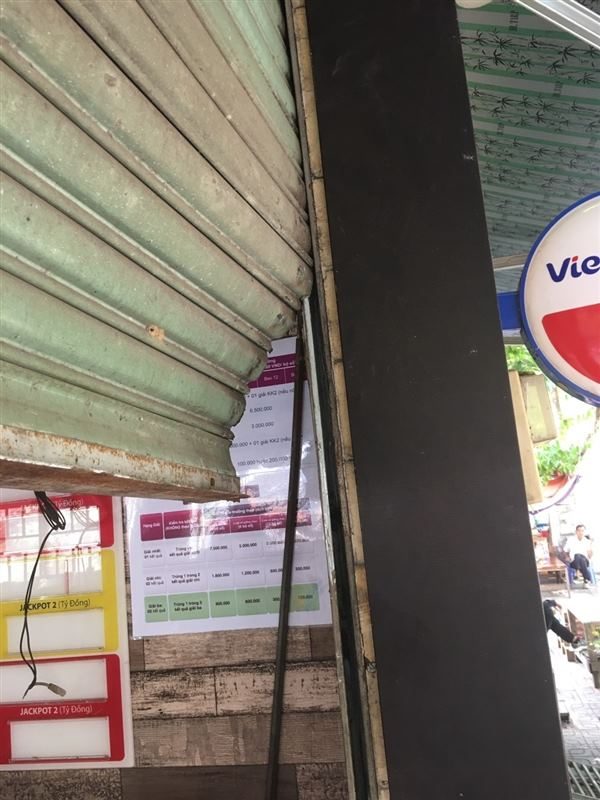 Phần dưới cửa cuốn màu xanh bị bung, lá cửa cong ra ngoài và lệch khỏi ray