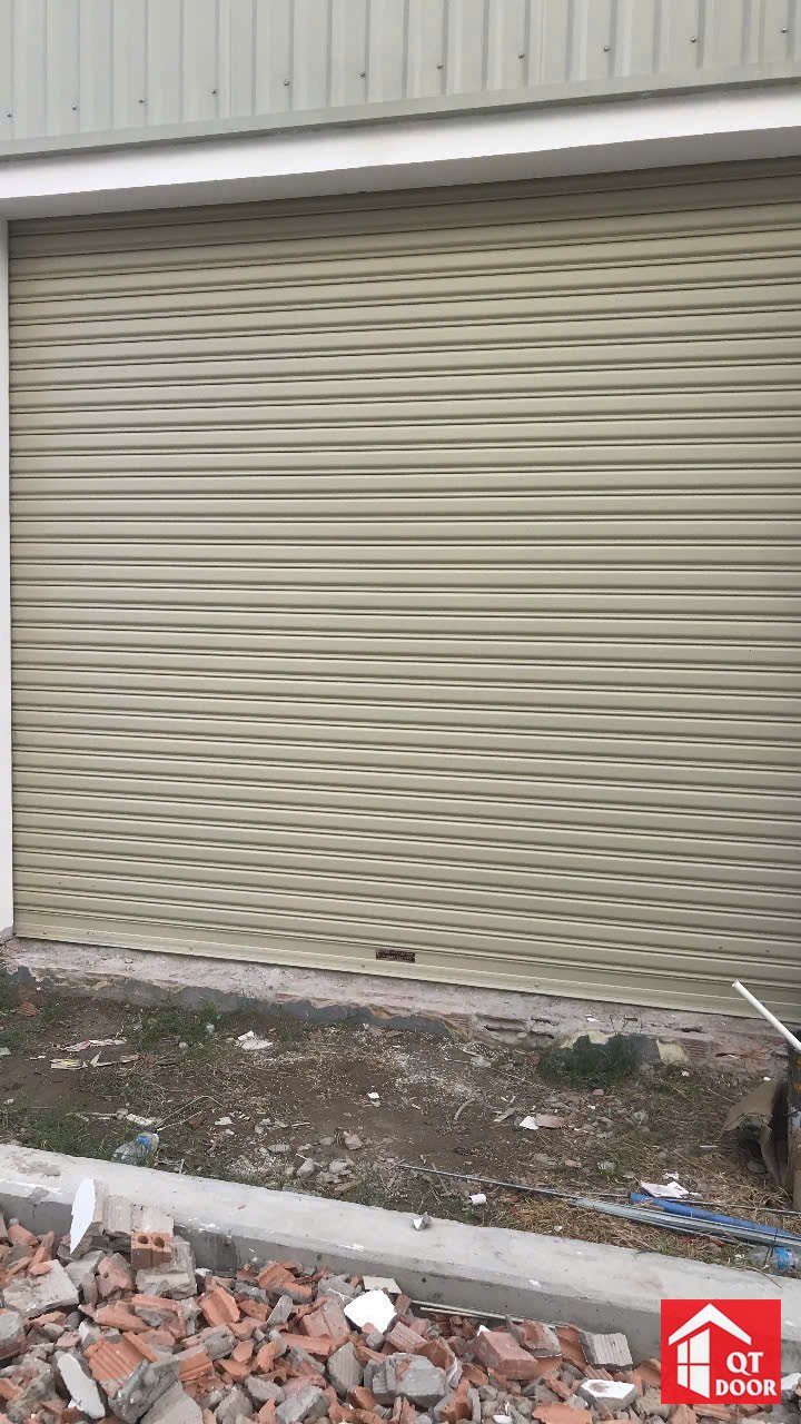 Cửa cuốn màu ghi lắp ở ô cửa nhà mới xây, phía trước còn gạch vụn